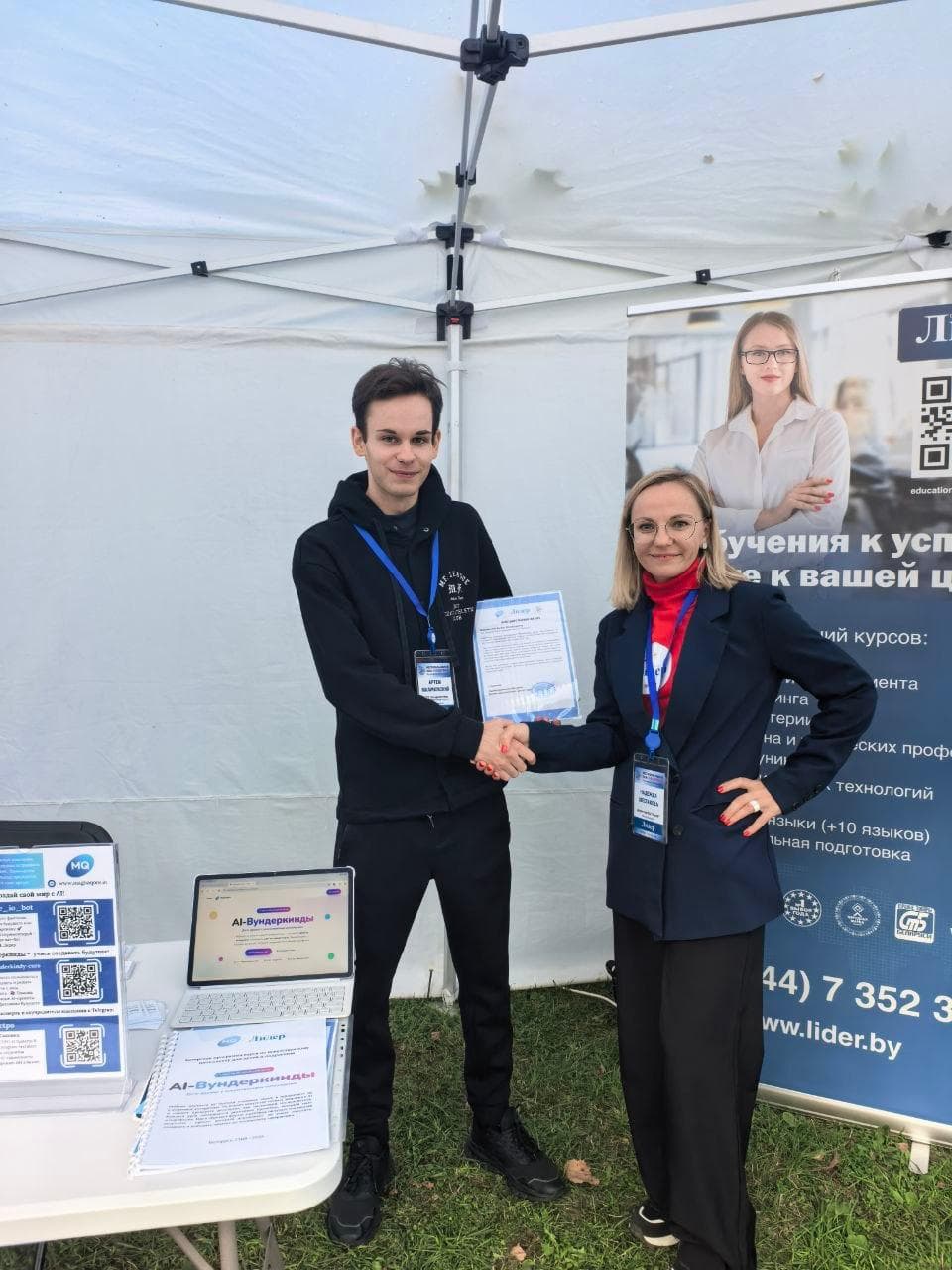 Artyom Malinouski of MagnaQore shaking hands with Nadia Shestakova, who holds a letter of appreciation, at the MagnaQore and Lider stand during Science Week